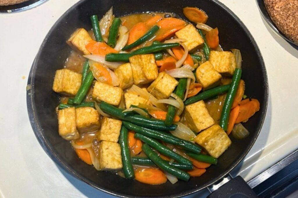 Miso sauce simmering and coating tofu and vegetables in the pan for miso tofu stir-fry.