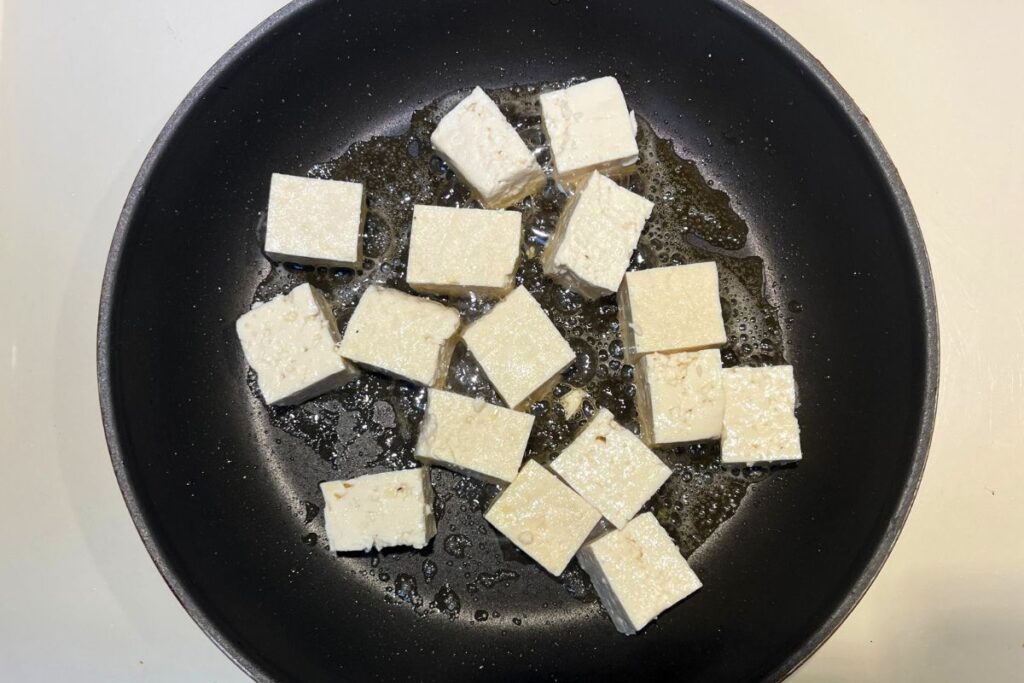 Cooking Miso Salmon in a Pan Tofu cubes frying in sesame oil until golden brown for miso tofu stir-fry.