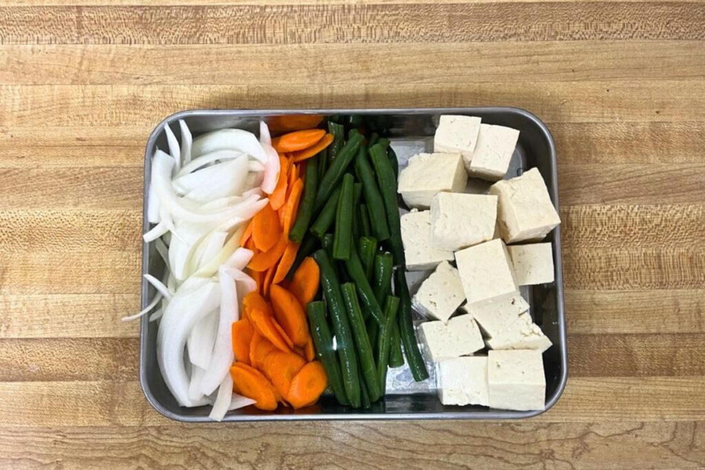 Brushing Miso Glaze on Salmon Fillets Tofu and veggies prepped for Trader Joe’s miso tofu stir-fry, including pressed tofu, sliced onion, julienned carrots, and green beans.