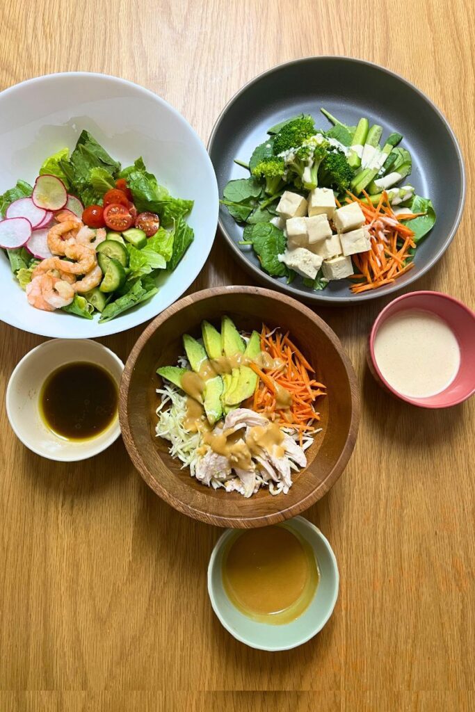 Three Japanese-style salads with different dressings on a dining table