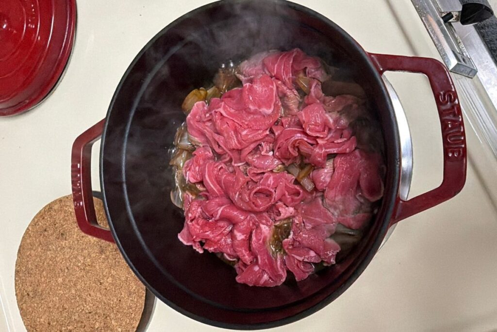 Onion simmering gently with soy sauce and maple syrup for gyudon