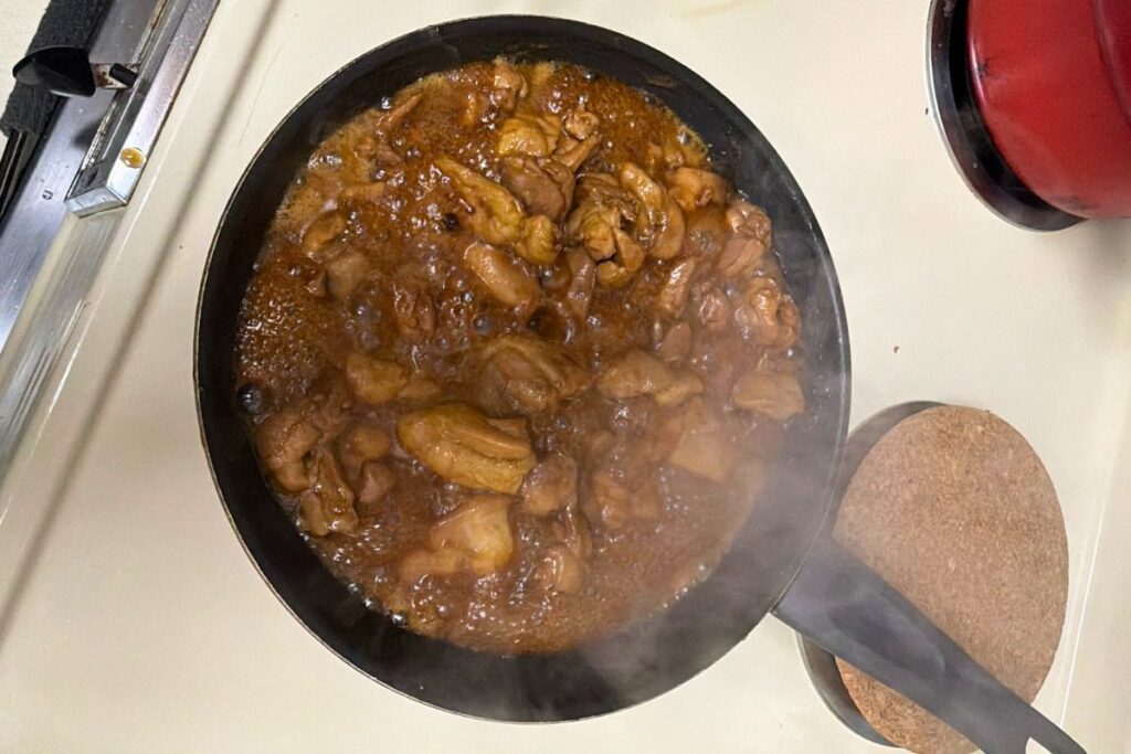 Adding teriyaki sauce to chicken in a pan