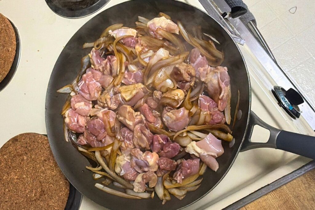 Boneless skinless chicken thighs added to the pan for oyakodon
